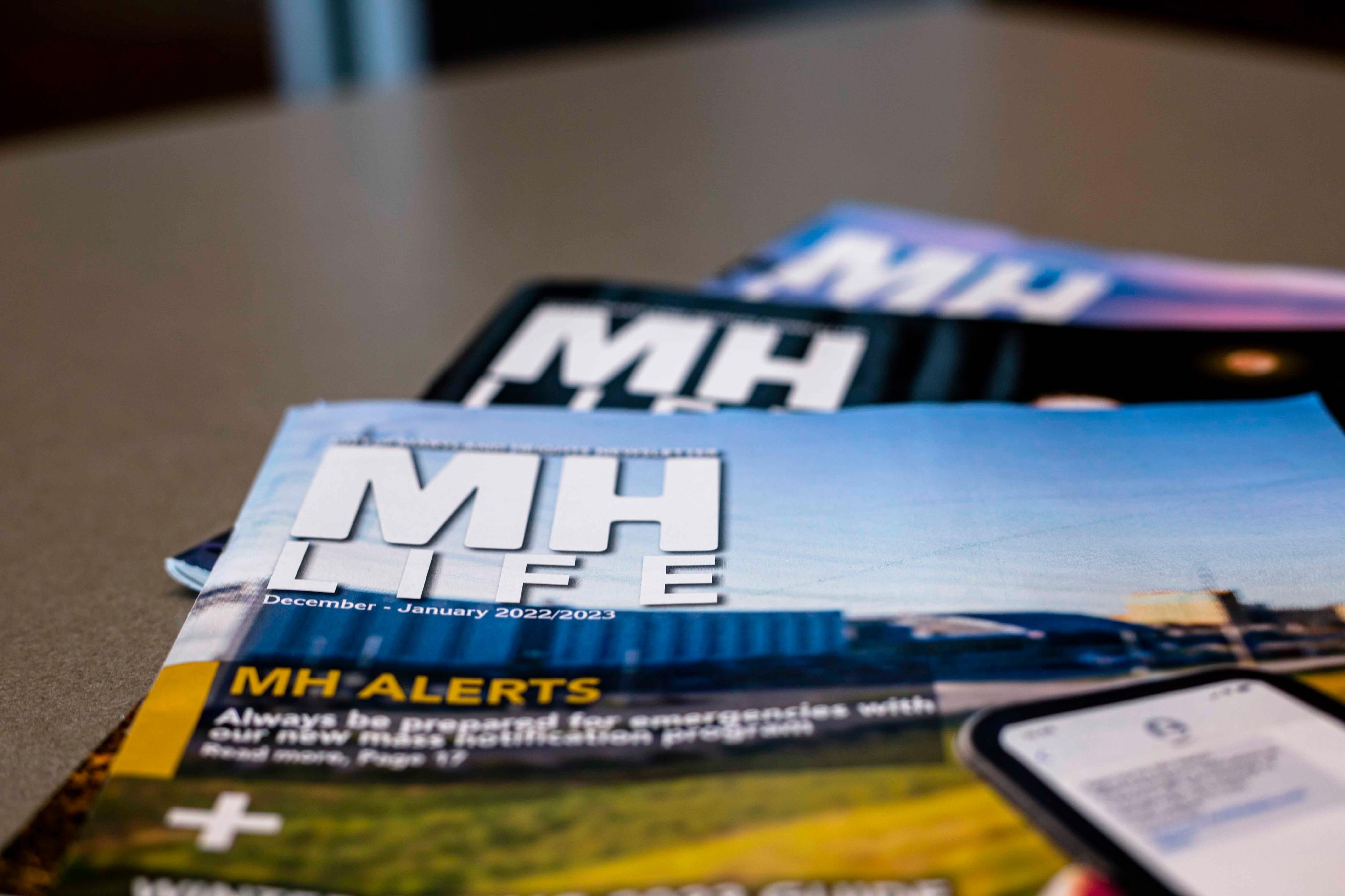 3 MH Life Newsletters stack on top of each other, with the MH Life Logo visible on the top right corner of each publication